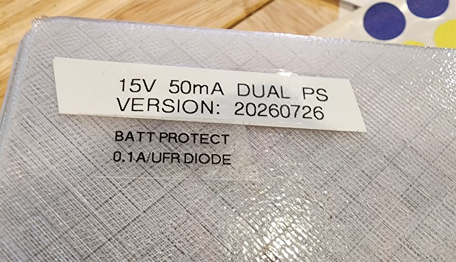 Label on a frosted enclosure reading 15V 50mA DUAL PS, VERSION 20260726, BATT PROTECT, 0.1A UFR DIODE.