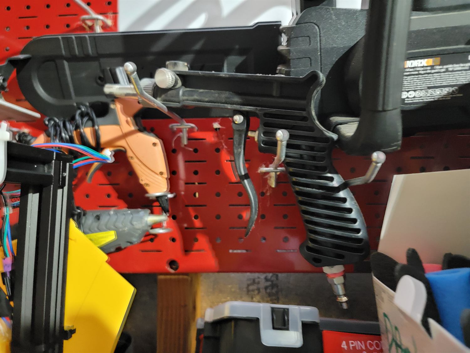 Pneumatic air tools hanging on a red pegboard above the project's aluminium extrusion frame and labelled gimbal wiring.